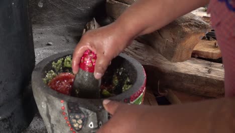 A-Mexican-woman-crushing-tomatoes-on-a-molcajete
