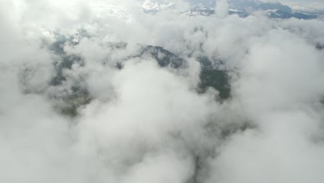 Dolly-out-slowly-with-drone-above-clouds-and-mountains-at-a-foggy-morning-in-Colombia