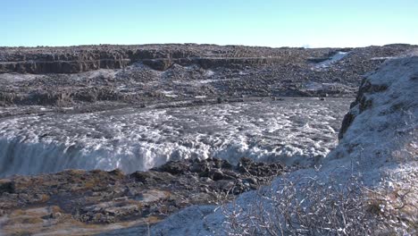 Massive-Dettifoss-river-waterfalls-in-Iceland-in-a-rocky-valley,-sunny