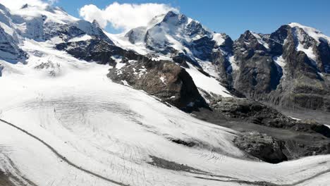 Aerial-flyover-over-Fuorcla-Trovat-peak-at-Diavolezza-in-Engadin,-Switzerland-with-a-view-of-Pers-glacier-and-other-peaks-of-the-Swiss-Alps-around-St