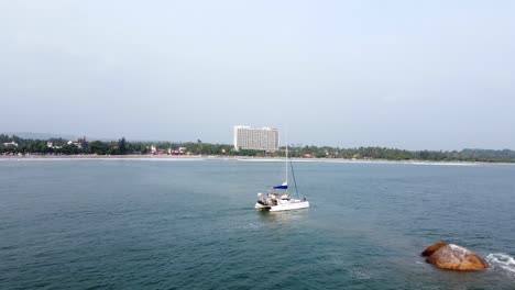 Pull-Back-Shot-Of-White-Boat-Sailing-In-Peace-In-Blue-Ocean,-Weligama,-Sri-Lanka