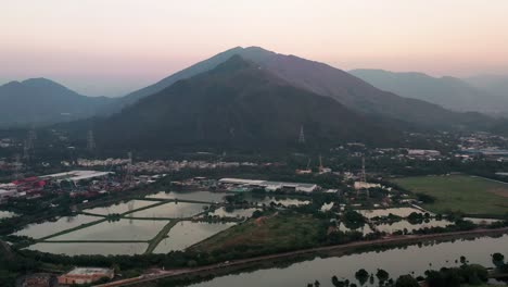 Aerial-dolly-in-of-Nam-Sang-Wai-fishpond-wetland-fields-surrounded-by-vegetation,-hills-in-background-on-an-overcast-day,-Hong-Kong,-China