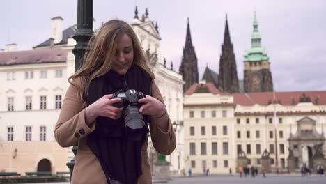 Chica-Fotógrafa-Revisando-Fotos-En-Cámara,-Castillo-De-Praga-En-Segundo-Plano,-República-Checa