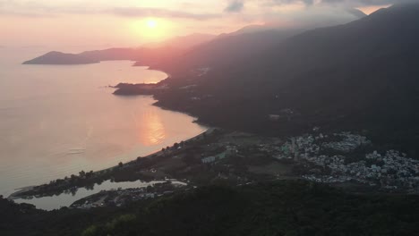 Aerial-parallax-of-Pui-O-beach-bay-and-sea-next-to-village-surrounded-by-rainforest-hills-at-golden-hour,-Lantau-Island,-Hong-Kong,-China