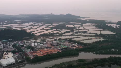 Aerial-parallax-of-fishpond-wetlands-fields-surrounded-by-vegetation-on-an-overcast-day-at-Nam-Sang-Wai,-Hong-Kong,-China