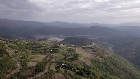 Front-drone-video-in-"golden-hour"-advancing-over-the-mountains-of-SH22-in-albania,-over-the-village-of-Va-Spas-and-in-the-background-Lake-Drin