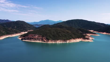 Aerial-parallax-of-High-Island-Reservoir-turquoise-water,-verdant-hills-and-hexagonal-rock-columns,-San-Kung-Peninsula-in-Hong-Kong,-China