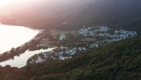 Aerial-parallax-of-Pui-O-beach-bay-and-sea-near-village-enclosed-in-rainforest-hills-at-golden-hour,-Lantau-Island,-Hong-Kong,-China
