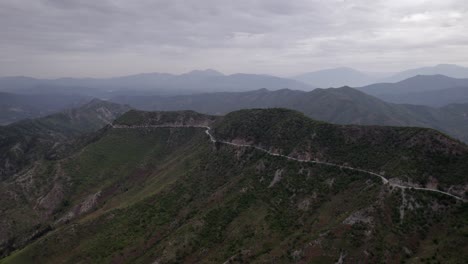 "golden-hour"-head-on-drone-video-moving-over-the-mountains-of-SH22-in-albania,-above-the-road-on-top-of-the-hill