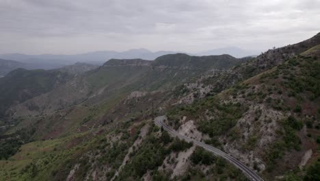 "golden-hour"-head-on-drone-video-moving-over-the-mountains-of-SH22-in-albania,-above-the-road-on-top-of-the-hill