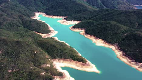 Aerial-truck-right-of-High-Island-Reservoir-verdant-hills,-rock-columns-shore-and-turquoise-water,-San-Kung-Peninsula-in-Hong-Kong,-China