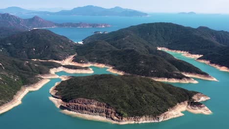 Aerial-orbit-of-High-Island-Reservoir-rock-columns-in-verdant-hills-shore-and-turquoise-water,-San-Kung-Peninsula-in-Hong-Kong,-China
