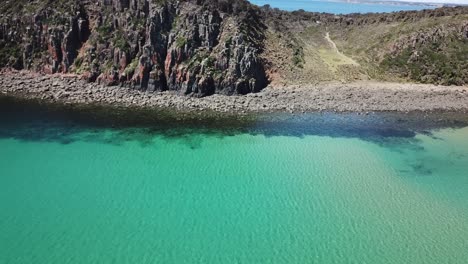Drone-aerial-over-tropical-blue-water-and-cliffside-moving-sideways