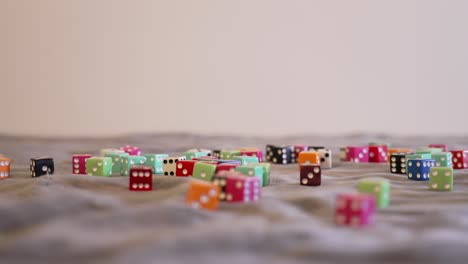 Rolling-brigh-red-glass-looking-dice-onto-a-large-pile-of-other-colored-dice