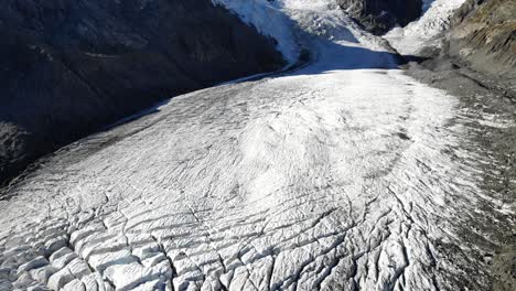 Aerial-flyover-over-Morteratsch-glacier-in-Engadin,-Switzerland-at-dawn-with-a-view-of-the-crevasses-and-Piz-Palu