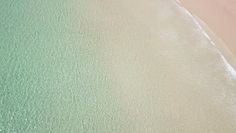 Drone-aerial-over-tropical-blue-water-and-beach-on-sunny-day