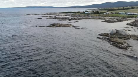Drone-aerial-parallax-on-rocky-and-remote-beach-in-Tasmania-on-cloudy-day