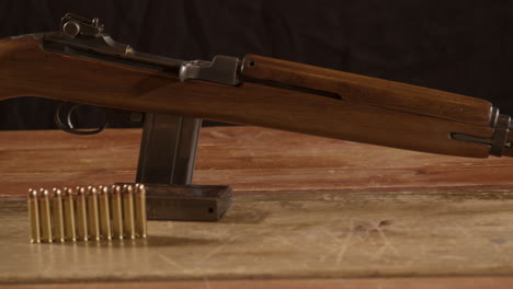 Wide-Dolly-of-classic-30m1-carbine-rifle-with-ammunition-on-the-foreground-standing-on-a-wooden-surface
