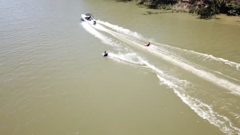 Drone-aerial-move-forward-over-river-with-speed-boat-and-water-skiing