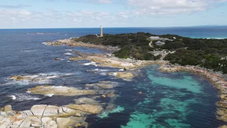 Drone-aerial-pan-up-to-reveal-lighthouse-and-forest-over-tropical-blue-water-Tasmania