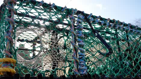 Sunlight-glare-through-stacked-empty-rope-lobster-crab-baskets-on-waterfront-harbour