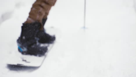 Man-On-Splitboard-Kicking-Up-Snow-Powder-Then-Pushing-Off-Poles-To-Take-Off-Down-Snowy-Trail