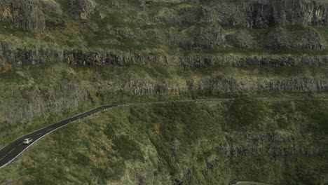 Car-driving-on-winding-steep-mountain-road-in-Madeira,-aerial
