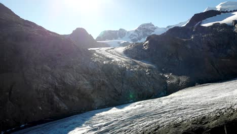 Aerial-flyover-across-the-Morteratsch-glacier-in-Engadin,-Switzerland-at-dawn-towards-the-spot-the-ice-used-to-connect-with-the-Pers-glacier-just-a-few-years-ago