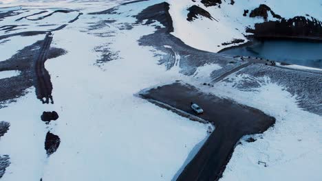 Car-parking-on-road-on-snowy-shore-of-a-lake-in-Viti-crater,-Iceland