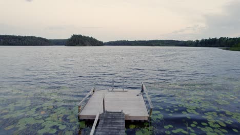 Private-overgrown-wooden-pier-at-Dusk,-Sweden,-POV-Drone-Reveal-shot
