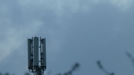 Gloomy-cloud-passing-moon-behind-cellular-telecommunication-transmission-tower