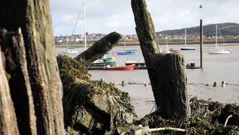 Rotten-derelict-old-pier-wood-debris-on-Conwy-harbour-waterfront-close-up-dolly-left-shot