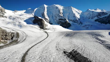 Aerial-flyover-over-Pers-glacier-near-Diavolezza-in-Engadin-Switzerland-with-a-pan-down-from-the-Piz-Bernina-peak-down-to-the-crevasses