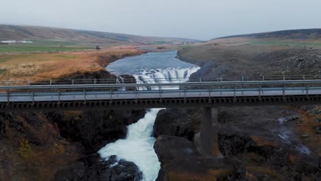 Drone-shot-of-a-bridge-above-Kolugljufur-waterfall-canyon-in-Iceland