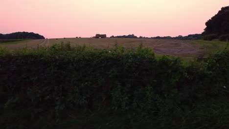 Sliding-shot-across-silhouette-farm-field-at-sunset