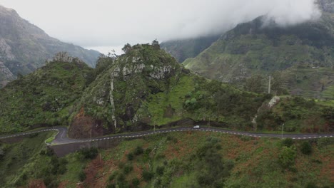 Vehicle-going-downhill-on-dangerous-winding-mountain-pass-road-on-ridge,-Madeira