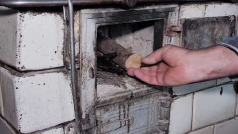 Man-opens-the-door-and-puts-wood-in-a-rustic-old-kitchen-stove