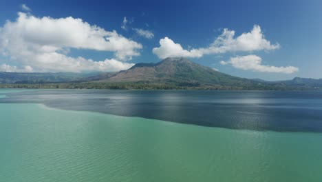 Clear-sunny-day-at-Lake-Batur-with-mount-Batur-in-background,-color-change-in-water-due-to-sulfur,-aerial