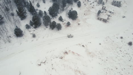 Drone-Aerial-View-of-Land-Rover-Defender-D90-SUV-Parked-on-Snowy-Backcountry-Alpine-Forest-Road-in-Rocky-Mountains-near-Nederland-Boulder-Colorado-USA-During-Heavy-Snowfall