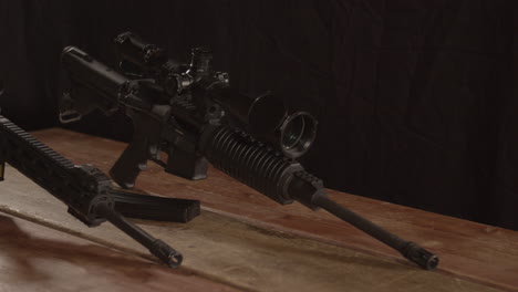 Dolly-in-of-two-AR-15-rifles-standing-on-a-wooden-table