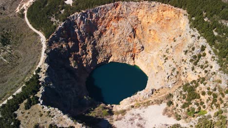 An-aerial-shot-of-Red-Lake-or-Crveno-jezero-which-is-a-collapsed-sinkhole-containing-a-karst-lake-close-to-Imotski,-Croatia