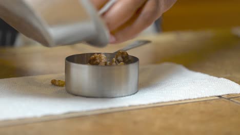 Measuring-a-half-cup-of-walnuts-to-make-a-crumble-topping-for-a-vegan-coffee-cake---isolated