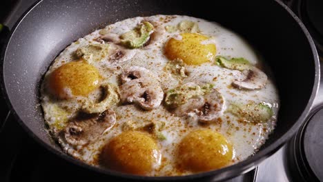 Frying-Eggs-With-Mushroom-And-Avocado-In-A-Skillet,-Seasoned-With-Salt-And-Pepper