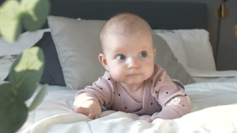 Close-up-of-a-little-Caucasian-baby-girl-lying-supine-moving-on-the-bed