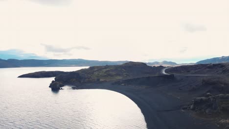 Road-along-black-volcanic-beaches-of-Kleifarvatn-lake,-Iceland,-drone