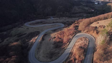 Aerial-view-of-a-car-driving-along-scenic-curvy-serpentine-road-in-the-mountains-with-ascending-and-tilt-movement