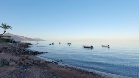 Boats-moored-on-shore-of-Dahab-city-at-sunset,-Egypt