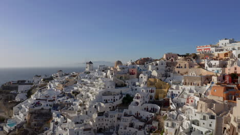 Slow-panning-drone-shot-of-Oia-in-Santorini,-Greece-during-golden-hour