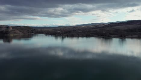 Dramatic-aerial-shot-over-the-lake-surface-establishing-the-view-of-the-rigid-Romanian-panorama-at-winter