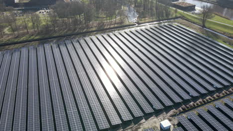 Aerial-of-bright-sun-reflection-shining-on-a-large-solar-panel-field-in-a-rural-area